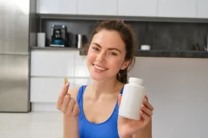 Una joven feliz y en forma haciendo deportes en casa muestra suplementos