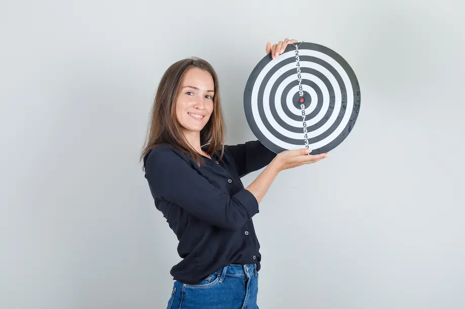Mujer joven en camisa negra, pantalones cortos de jeans sosteniendo un juego