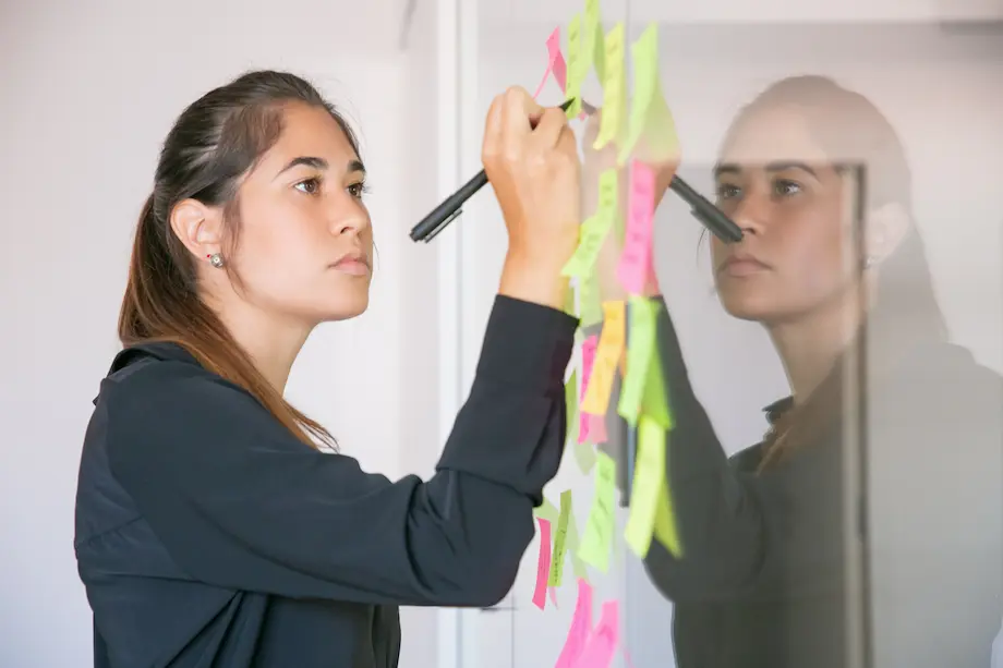 Joven empresaria escribiendo en etiqueta con marcador
