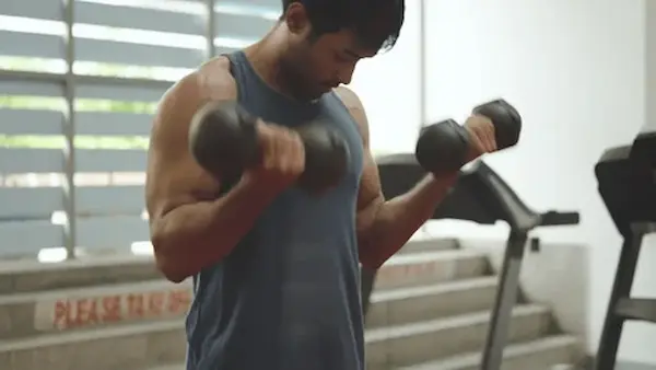 Hombre adulto levantando pesas en gimnasio, entrenando fuerza y resistencia
