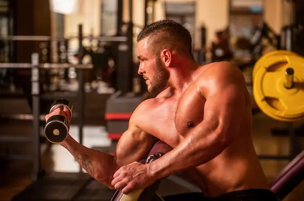 Hombre levantando pesas en gimnasio, entrenando fuerza en ejercicios para hombres